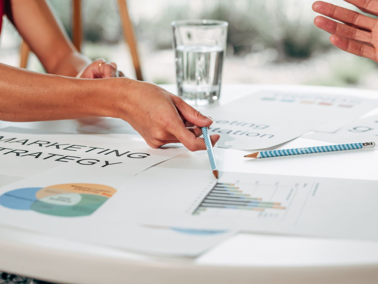 Des mains échangent sur une stratégie marketing autour de graphiques, dans un environnement de bureau.